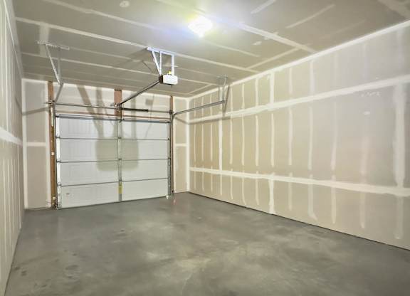 A room with a garage door and a concrete floor.