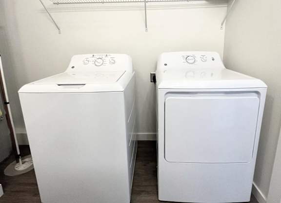 Two white front loading washing machines in a laundry room.