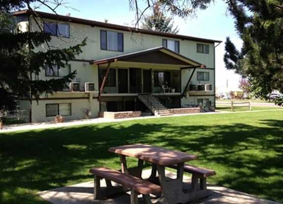 A picnic table is in front of a two-story house.