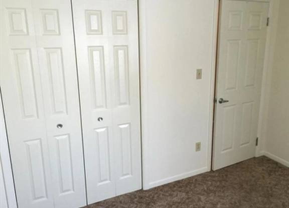 A room with a carpeted floor and a white door.