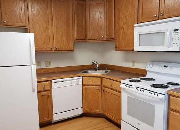 A kitchen with wooden cabinets and white appliances.