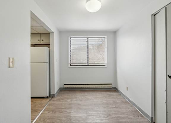 A white room with a window and a refrigerator.