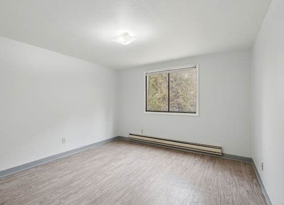A room with a window and a painting on the wall.