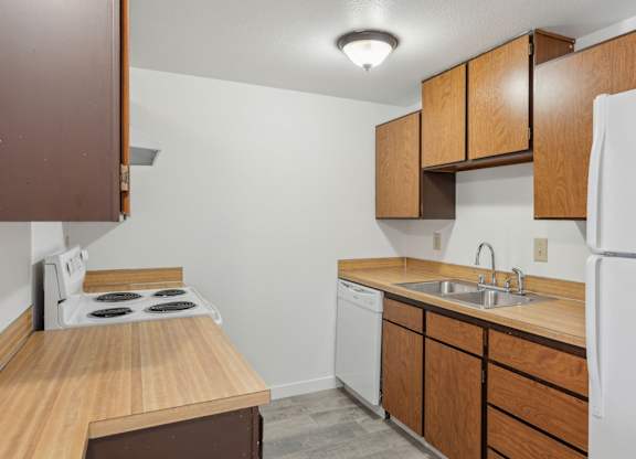 A kitchen with a white refrigerator, white dishwasher, and a white stove top.