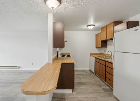 A kitchen with a white refrigerator and wooden countertops.