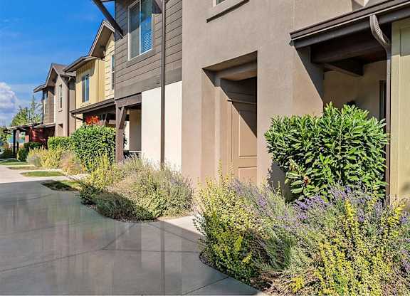 A row of houses with a well-kept garden in front.