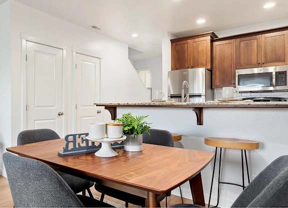 A modern dining room with a wooden table and grey chairs.