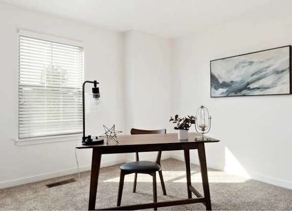 A room with a table, chair, and a painting on the wall.