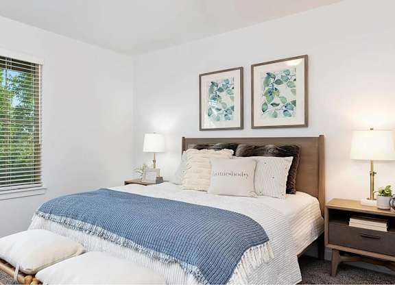 A bedroom with a bed, nightstand, and two framed pictures on the wall.