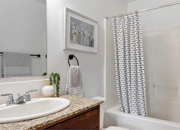 A bathroom with a white tub, a sink, and a shower curtain.