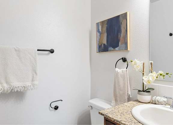 A white bathroom with a towel hanging on the towel rack.