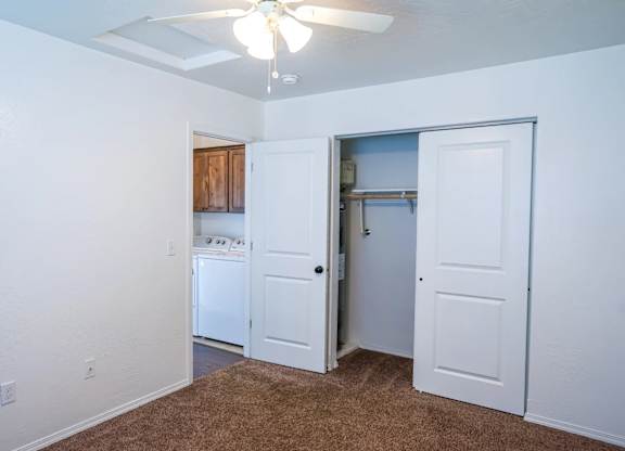 A room with a brown carpet and a ceiling fan.