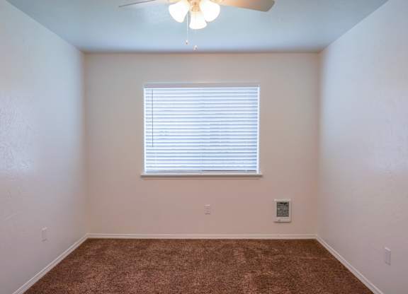 A room with a ceiling fan and a window with blinds.