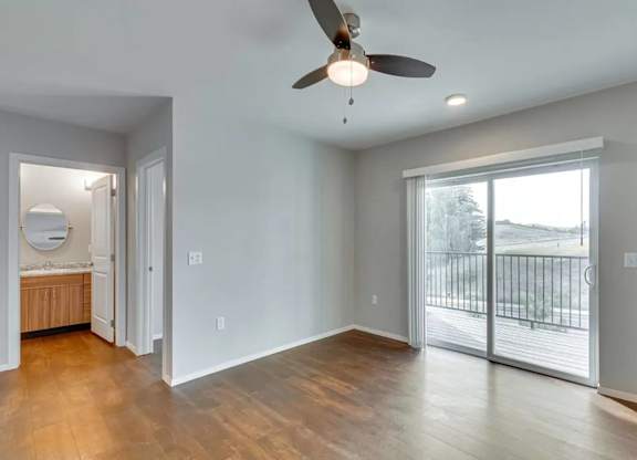 A room with a ceiling fan and sliding glass doors.