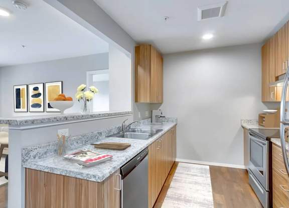 A kitchen with a marble countertop and wooden cabinets.