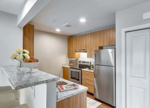 A kitchen with a marble table and a refrigerator.