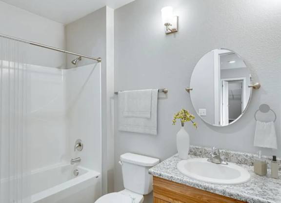 A white bathroom with a sink, toilet, and shower.