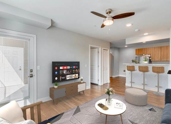 A modern living room with a flat screen TV and a ceiling fan.