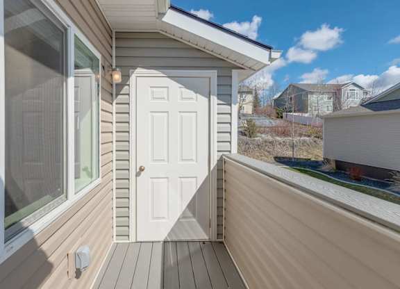 A small white door is on the side of a house.