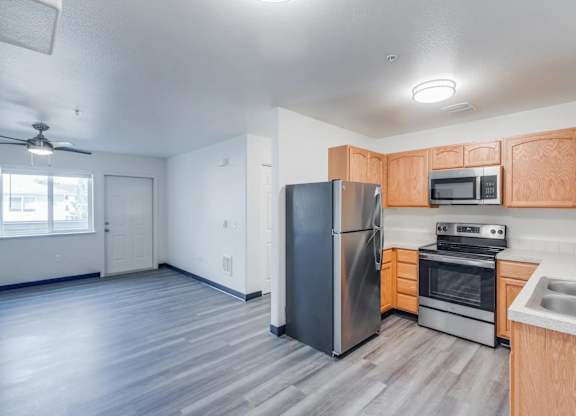 A kitchen with a refrigerator, oven, microwave, and sink.