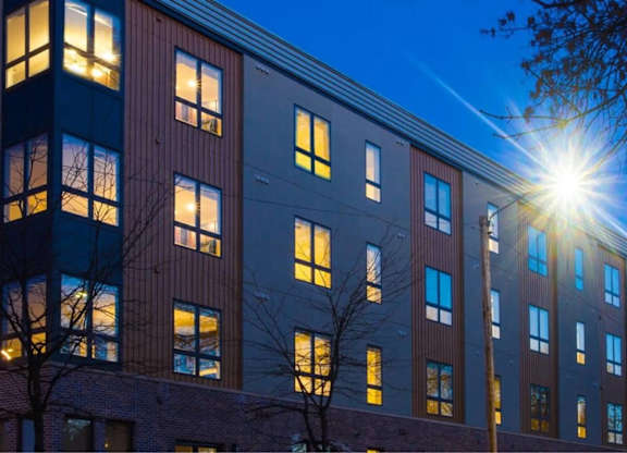 A building with a tree in front of it is illuminated by a bright light.