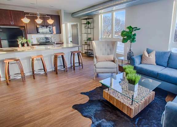 A living room with a blue couch and a glass coffee table.