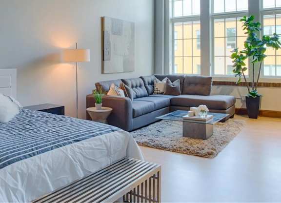 A bedroom with a large bed and a grey couch.