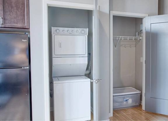 A small kitchen with a refrigerator, a sink, and a small white bathtub.