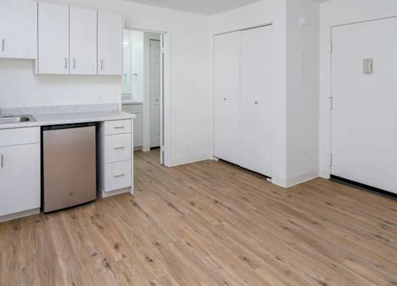 A kitchen with white cabinets and a wooden floor.