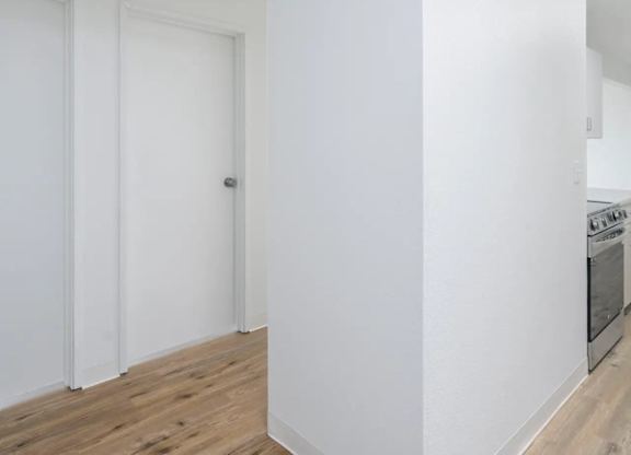 A kitchen with white walls and wooden floors.