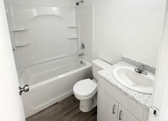 A white bathroom with a toilet, sink, and bathtub.