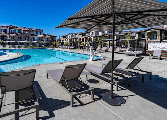 A poolside area with sun loungers and a shade umbrella.