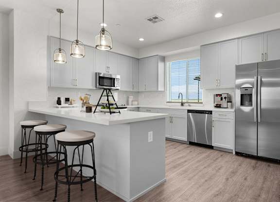 a kitchen with stainless steel appliances and a large island with three stools