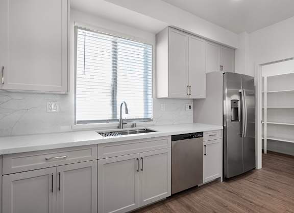 a renovated kitchen with white cabinets and stainless steel appliances