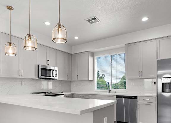 a white kitchen with stainless steel appliances and white counter tops