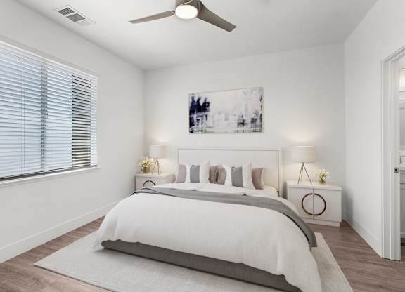 a white bedroom with a bed and a ceiling fan
