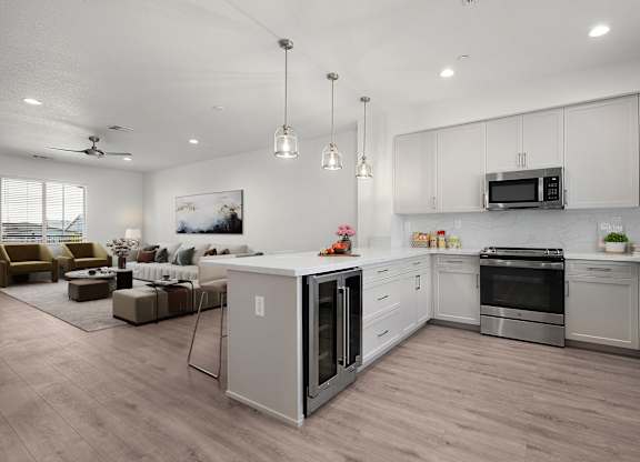 an open kitchen and living room with white cabinets and a counter top