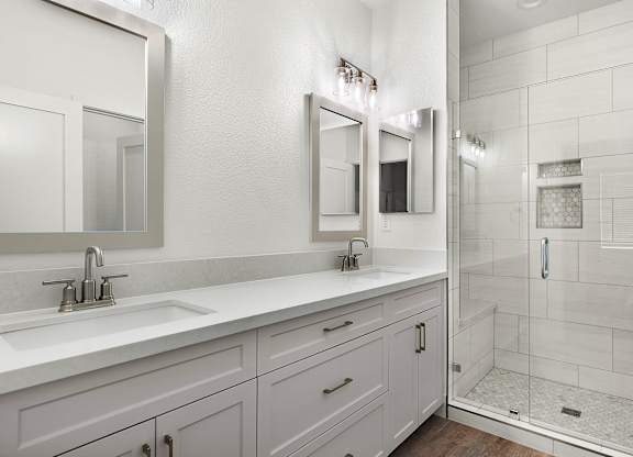 a white bathroom with two sinks and a shower