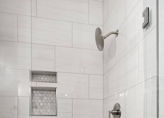 a large shower with white tiles in a bathroom