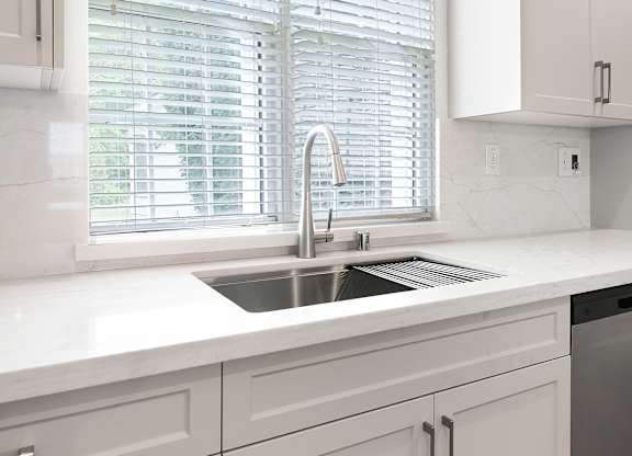 a kitchen with white cabinets and a sink and a window
