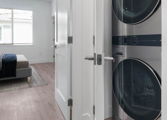 a washer and dryer in a living room with a door to a bedroom