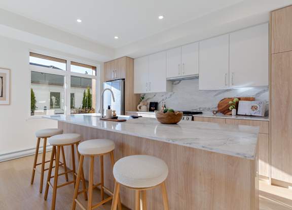 A kitchen with a marble countertop and wooden stools in Hillcrest Ave located in Abbotsford, BC