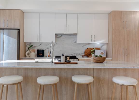 A kitchen with white cabinets and a marble backsplash in Hillcrest Ave located in Abbotsford, BC