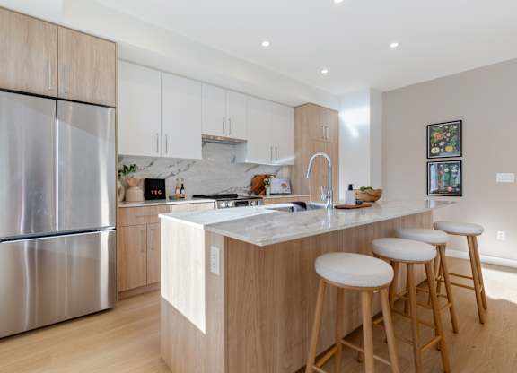 A modern kitchen with a stainless steel refrigerator and wooden cabinets in Hillcrest Ave located in Abbotsford, BC