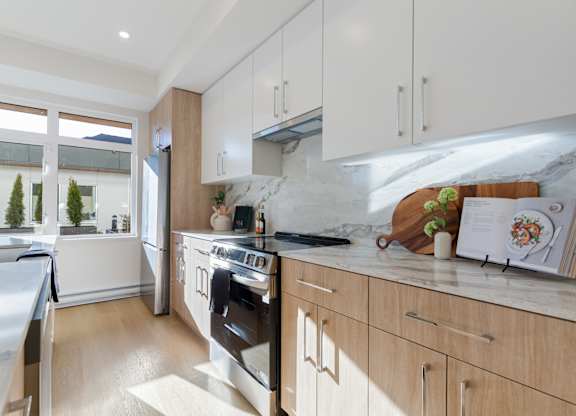 A modern kitchen with a stainless steel refrigerator and wooden cabinets in Hillcrest Ave located in Abbotsford, BC