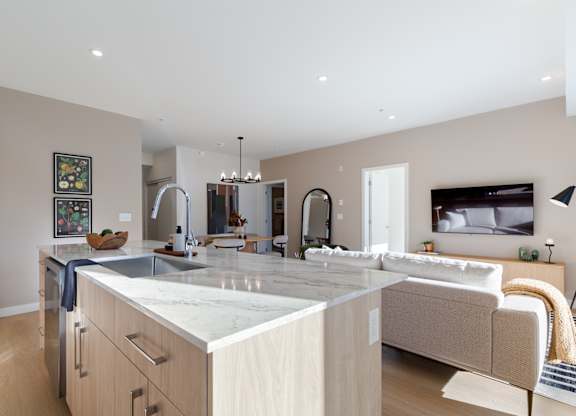 A modern kitchen with a large island and a living area with a couch in Hillcrest Ave located in Abbotsford, BC