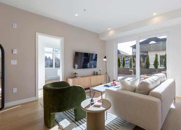 A living room with a green chair and a beige couch in Hillcrest Ave located in Abbotsford, BC