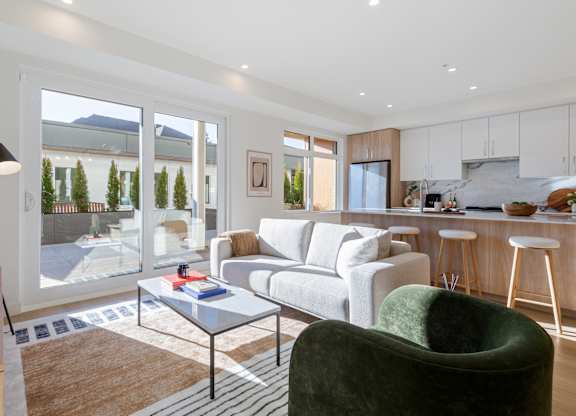 A modern living room with a green armchair and a glass table in Hillcrest Ave located in Abbotsford, BC