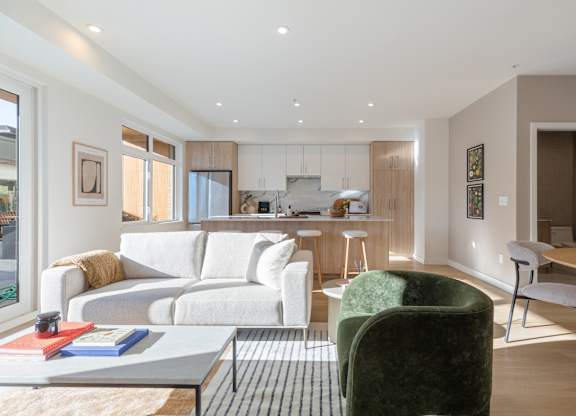 A modern living room with a white sofa, green armchair, and a coffee table in Hillcrest Ave located in Abbotsford, BC