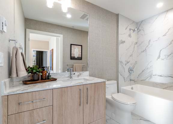 A bathroom with a marble wall and a white bathtub in Hillcrest Ave located in Abbotsford, BC